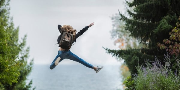 benefits of time management - woman jumping in air near trees