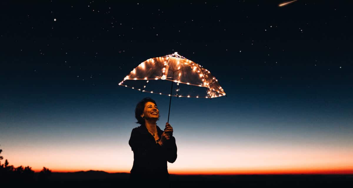 benefits of goal setting - woman holding umbrella that has lights against the night sky