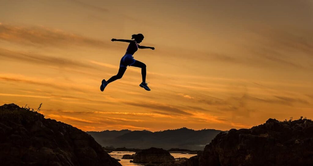how to set goals - woman jumping over ravine